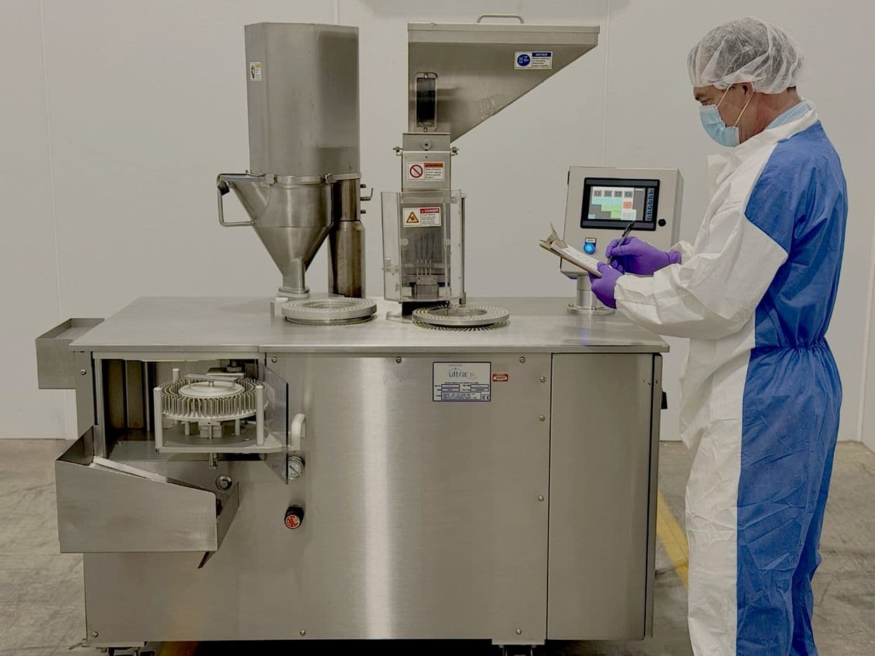 Capsule production operator working with manufacturing equipment